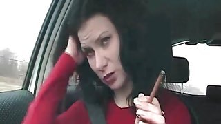 Brunette in the car smokes cigarette lustily